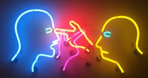The outline of two heads lit up in neon constantly point at each other in anger. The picture is used to symbolise how a student feels when the examiner interrupts them in the IELTS exam by an examiner