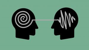 The shadow of two heads a placed on a green background. In one head there is a white spiral, which loops and connected to a scribbled mess inside the head opposite. The picture symbolises how an IELTS test-taker might not understand the functions they are asked to discuss in the in the speaking exam.